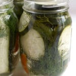 A mason jar filled with cucumber slices, dill, and pickling liquid