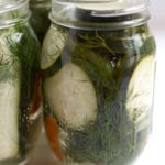 A mason jar filled with cucumber slices, dill, and habanero peppers