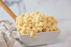 White square shaped bowl filled with mac and cheese made with curly pasta