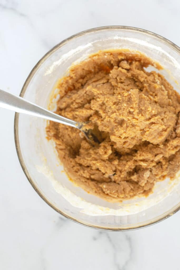 Overhead view of a clear bowl of peanut butter cookie batter