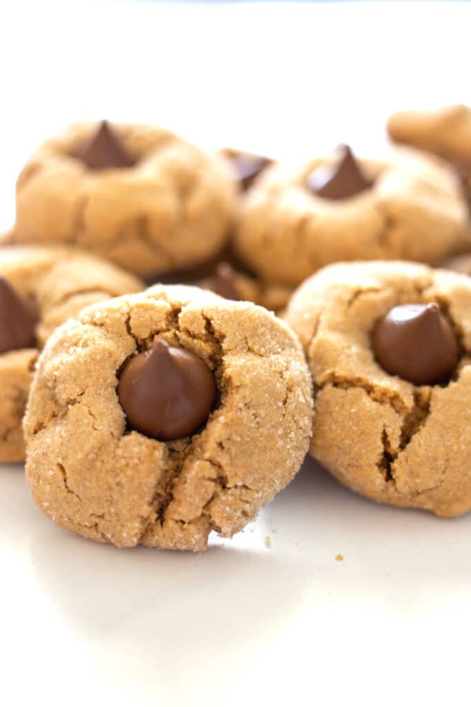 A pile of peanut butter kiss cookies on a white background