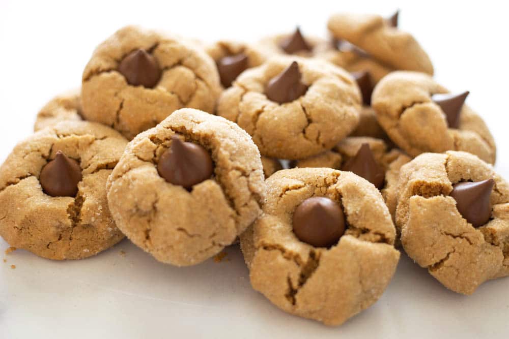 A pile of peanut butter kiss cookies on a white background