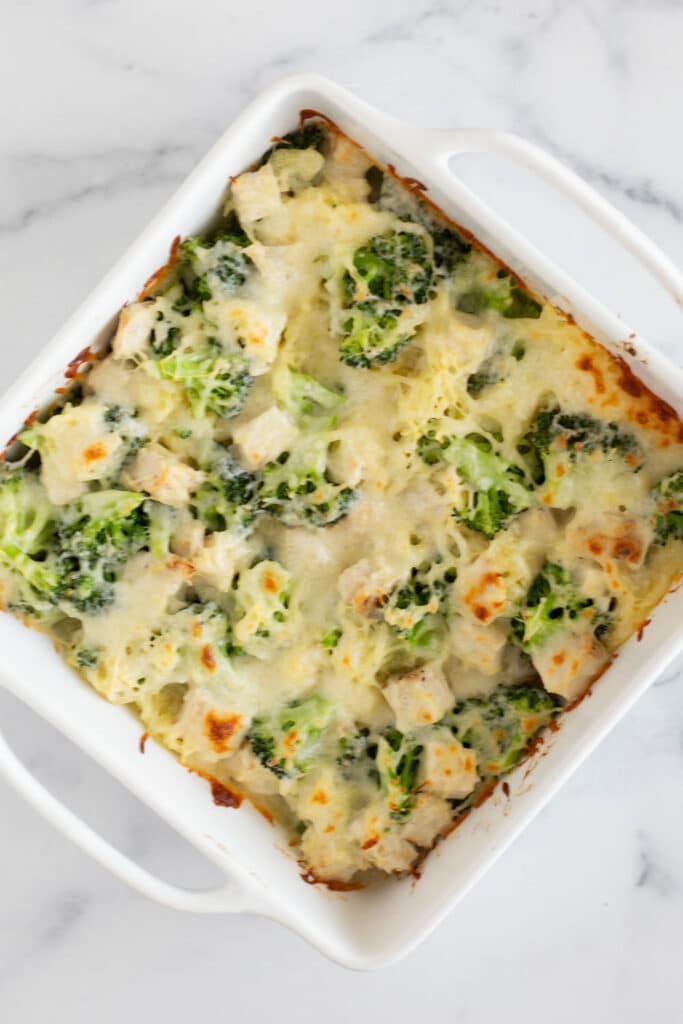 A white baking dish with baked chicken, broccoli, cheese, and spaghetti squash casserole