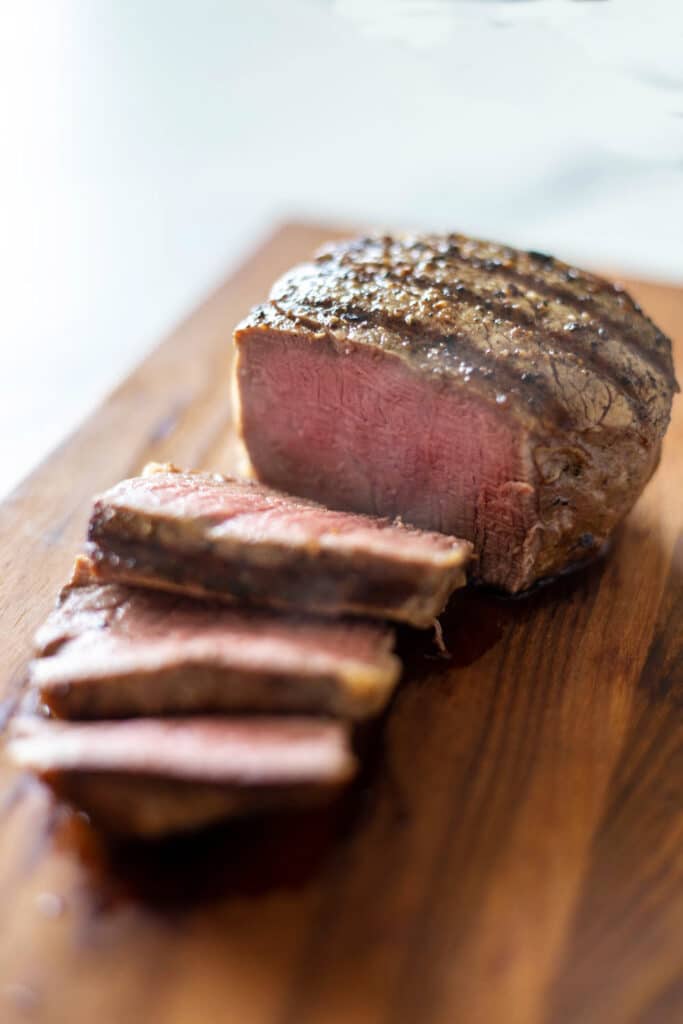 Partially sliced steak on a wood cutting board