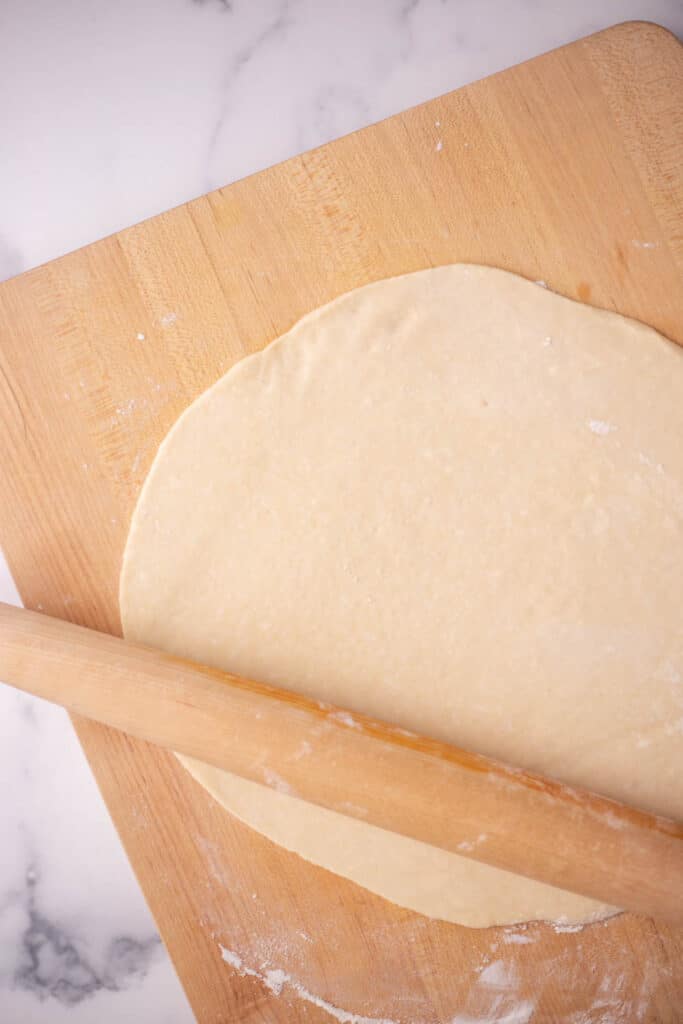 Cutting board with a rolling pin and rolled out pie dough